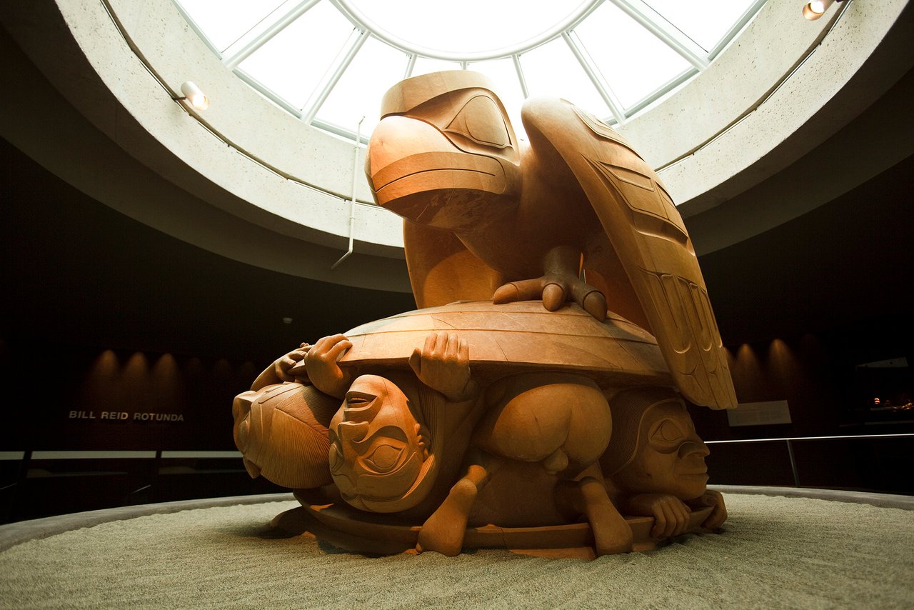 A large carving of Raven sitting on a clam shell with humans emerging ...